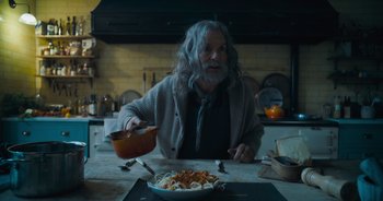 Movie still from “The Flash” (2023), directed by Andy Muschietti – An older man sitting at a table with a bowl of pasta; Medium shot, High angle