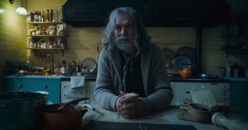 Movie still from “The Flash” (2023), directed by Andy Muschietti – An older man sitting at a table in a kitchen; Medium shot, Over the shoulder angle