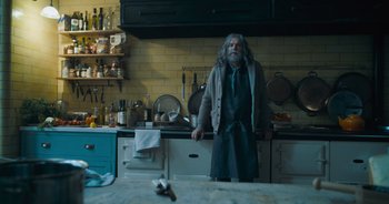 Movie still from “The Flash” (2023), directed by Andy Muschietti – An old man standing in a kitchen next to a counter; Wide shot, Low angle