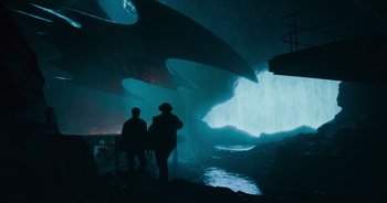Movie still from “The Flash” (2023), directed by Andy Muschietti – Two people standing in front of an underwater cave; Extreme Wide shot, Low angle
