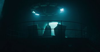 Movie still from “The Flash” (2023), directed by Andy Muschietti – A dark room lit by a light that is shining on the ground; Wide shot, Low angle