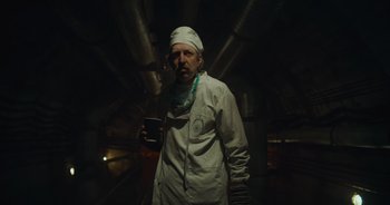Movie still from “The Flash” (2023), directed by Andy Muschietti – A man in a white lab coat holding a cup; Medium shot, Low angle