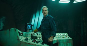 Movie still from “The Flash” (2023), directed by Andy Muschietti – A man standing next to a control panel; Medium shot, Low angle