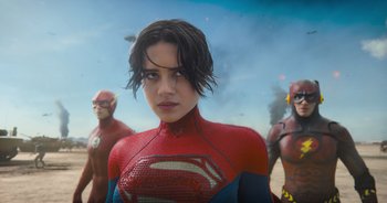 Movie still from “The Flash” (2023), directed by Andy Muschietti – A woman in a superman costume with two other men in the background; Medium shot, Over the shoulder angle