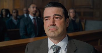 Movie still from “The Flash” (2023), directed by Andy Muschietti – A person wearing a suit and tie; Close Up shot, High angle