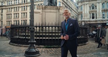 Movie still from “The Flash” (2023), directed by Andy Muschietti – An older man in a suit standing next to a street light; Wide shot, Low angle