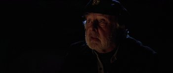 Movie still from “The Fog” (1980), directed by John Carpenter – An older man wearing a hat and a black jacket; Close Up shot, Over the shoulder angle