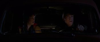 Movie still from “The Fog” (1980), directed by John Carpenter – A man and a woman sitting in the back seat of a car; Close Up shot, Over the shoulder angle