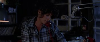 Movie still from “The Fog” (1980), directed by John Carpenter – A person sitting at a table talking on a phone; Medium shot, High angle