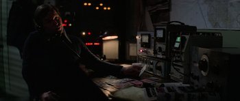 Movie still from “The Fog” (1980), directed by John Carpenter – A person is playing cards on a table in a dark room; Medium shot, Over the shoulder angle