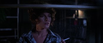Movie still from “The Fog” (1980), directed by John Carpenter – A woman smoking a cigarette while looking out of a window; Close Up shot, Low angle