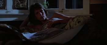 Movie still from “The Fog” (1980), directed by John Carpenter – A woman laying in a bed in a dark room; Medium shot, High angle