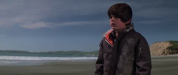 Movie still from “The Fog” (1980), directed by John Carpenter – A young boy standing on the beach in front of the ocean; Medium shot, Low angle