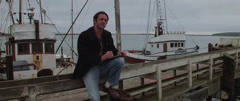 Movie still from “The Fog” (1980), directed by John Carpenter – A man sitting on a bench near the water; Medium shot, Low angle