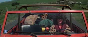 Movie still from “The Fog” (1980), directed by John Carpenter – A woman is driving a vehicle with a bunch of things on the windshield; Wide shot, High angle