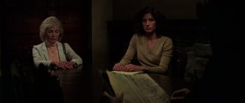 Movie still from “The Fog” (1980), directed by John Carpenter – A woman sitting at a table reading a newspaper; Medium shot, Over the shoulder angle