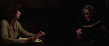 Movie still from “The Fog” (1980), directed by John Carpenter – Two people sitting at a dinner table writing on a piece of paper; Medium shot, Over the shoulder angle