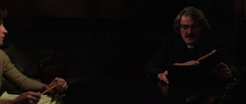 Movie still from “The Fog” (1980), directed by John Carpenter – A man sitting at a table in a dimly - lit room; Medium shot, High angle