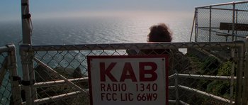 Movie still from “The Fog” (1980), directed by John Carpenter – A person looking out over the ocean from a pier; Extreme Wide shot, High angle