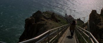 Movie still from “The Fog” (1980), directed by John Carpenter – A person walking on a boardwalk near the ocean; Extreme Wide shot, High angle