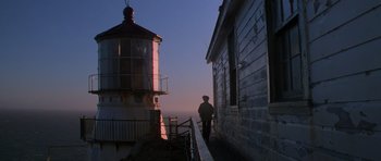 Movie still from “The Fog” (1980), directed by John Carpenter – A man standing on the steps leading to a light house; Extreme Wide shot, Low angle