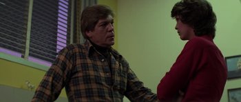 Movie still from “The Fog” (1980), directed by John Carpenter – A man in a plaid shirt talking to another man; Medium shot, Over the shoulder angle