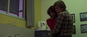 Movie still from “The Fog” (1980), directed by John Carpenter – A man and a woman sitting next to each other in a room; Medium shot, High angle