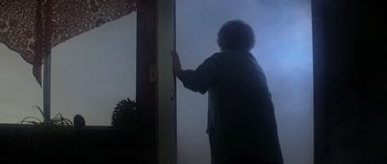 Movie still from “The Fog” (1980), directed by John Carpenter – An older woman opening the door of a house; Wide shot, Low angle
