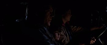 Movie still from “The Fog” (1980), directed by John Carpenter – A man and a woman and a child are watching a movie together; Close Up shot, High angle