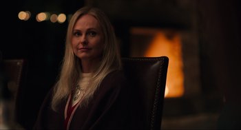 Movie still from “The Forever Purge” (2021), directed by Everardo Gout – A woman sitting in a chair in front of a fire place; Close Up shot, Over the shoulder angle