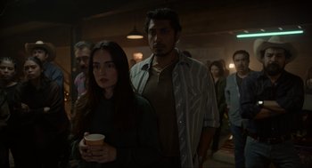 Movie still from “The Forever Purge” (2021), directed by Everardo Gout – A group of people standing in a room holding drinks; Medium shot, Over the shoulder angle