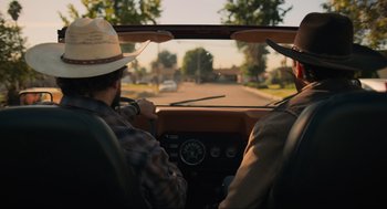 Movie still from “The Forever Purge” (2021), directed by Everardo Gout – Two men driving a car down a street; Medium shot, Low angle