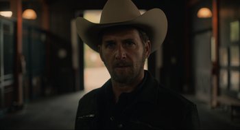 Movie still from “The Forever Purge” (2021), directed by Everardo Gout – A man wearing a cowboy hat in a dark room; Close Up shot, Over the shoulder angle