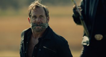 Movie still from “The Forever Purge” (2021), directed by Everardo Gout – A man with his mouth taped shut and looking at the camera; Close Up shot, Over the shoulder angle