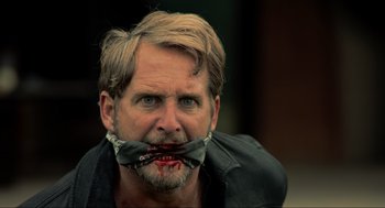 Movie still from “The Forever Purge” (2021), directed by Everardo Gout – A man with blood on his face and mouth; Close Up shot, Over the shoulder angle
