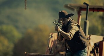 Movie still from “The Forever Purge” (2021), directed by Everardo Gout – A man in a cowboy hat is holding a gun; Medium shot, Low angle