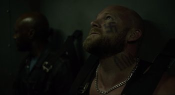 Movie still from “The Forever Purge” (2021), directed by Everardo Gout – A man with a beard and tattoos looking up; Close Up shot, Low angle