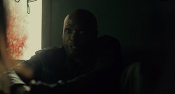 Movie still from “The Forever Purge” (2021), directed by Everardo Gout – A man sitting in a dark room with his head turned to the side; Close Up shot, Over the shoulder angle