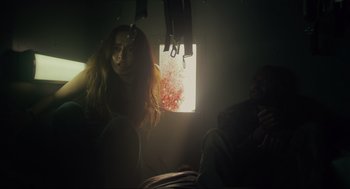 Movie still from “The Forever Purge” (2021), directed by Everardo Gout – A woman sitting in a dark room next to a window; Medium shot, Low angle