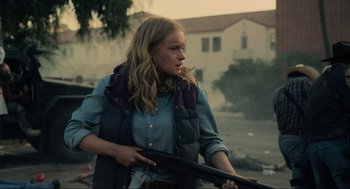 Movie still from “The Forever Purge” (2021), directed by Everardo Gout – A woman holding a gun in a residential area; Medium shot, Over the shoulder angle