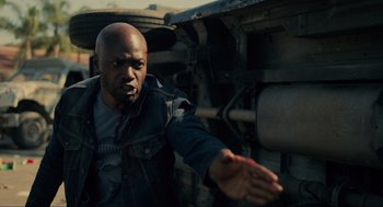 Movie still from “The Forever Purge” (2021), directed by Everardo Gout – A bald man in a black jacket is reaching out his hand; Medium shot, Low angle