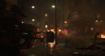 Movie still from “The Forever Purge” (2021), directed by Everardo Gout – A person holding a gun in the rain at night; Medium shot, Low angle