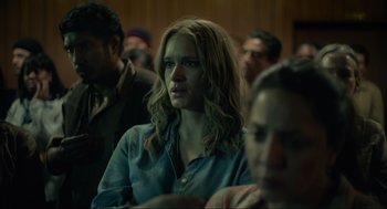 Movie still from “The Forever Purge” (2021), directed by Everardo Gout – A woman with long blonde hair sitting in front of a group of people; Close Up shot, Over the shoulder angle