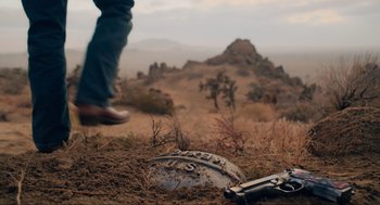 Movie still from “The Forever Purge” (2021), directed by Everardo Gout – A man standing in a field next to an object; Wide shot, Low angle