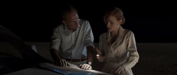 Movie still from “The Forgiven” (2021), directed by John Michael McDonagh – A man and a woman working together on a project; Medium shot, High angle