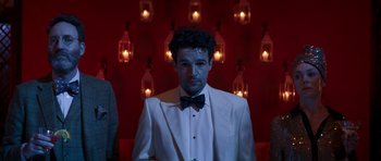 Movie still from “The Forgiven” (2021), directed by John Michael McDonagh – A man in a white suit and a bow tie; Medium shot, Over the shoulder angle