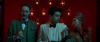 Movie still from “The Forgiven” (2021), directed by John Michael McDonagh – A man in a white suit and a bow tie; Medium shot, Low angle