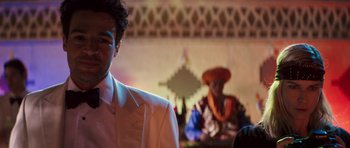 Movie still from “The Forgiven” (2021), directed by John Michael McDonagh – A man in a white suit and a man in an orange hat; Close Up shot, Over the shoulder angle