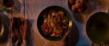 Movie still from “The Forgiven” (2021), directed by John Michael McDonagh – A person holding a green bowl of fruit; Extreme Close Up shot, Overhead angle