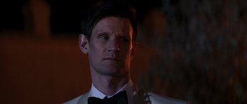 Movie still from “The Forgiven” (2021), directed by John Michael McDonagh – A person wearing a suit and bow tie; Close Up shot, Over the shoulder angle